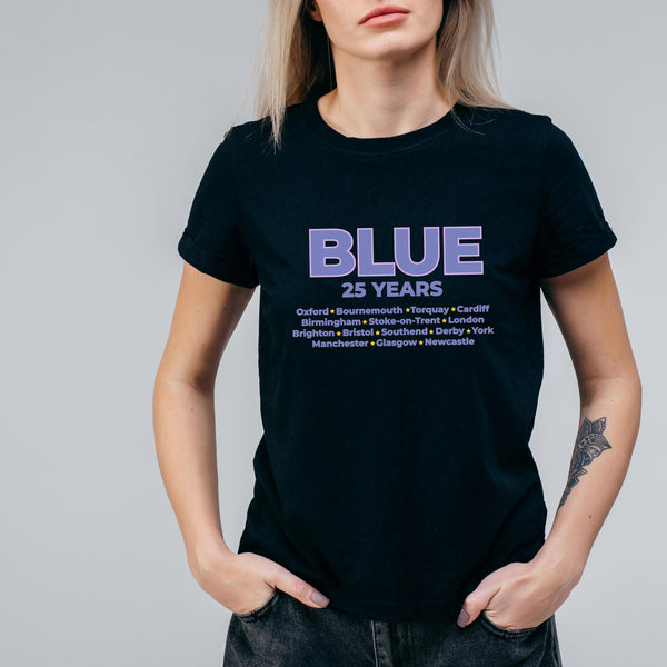 May include: Black t-shirt featuring the word "BLUE" in purple, with "25 YEARS" beneath. A list of UK cities, including Oxford, Birmingham, and Brighton, is printed below. The shirt has a crew neck.